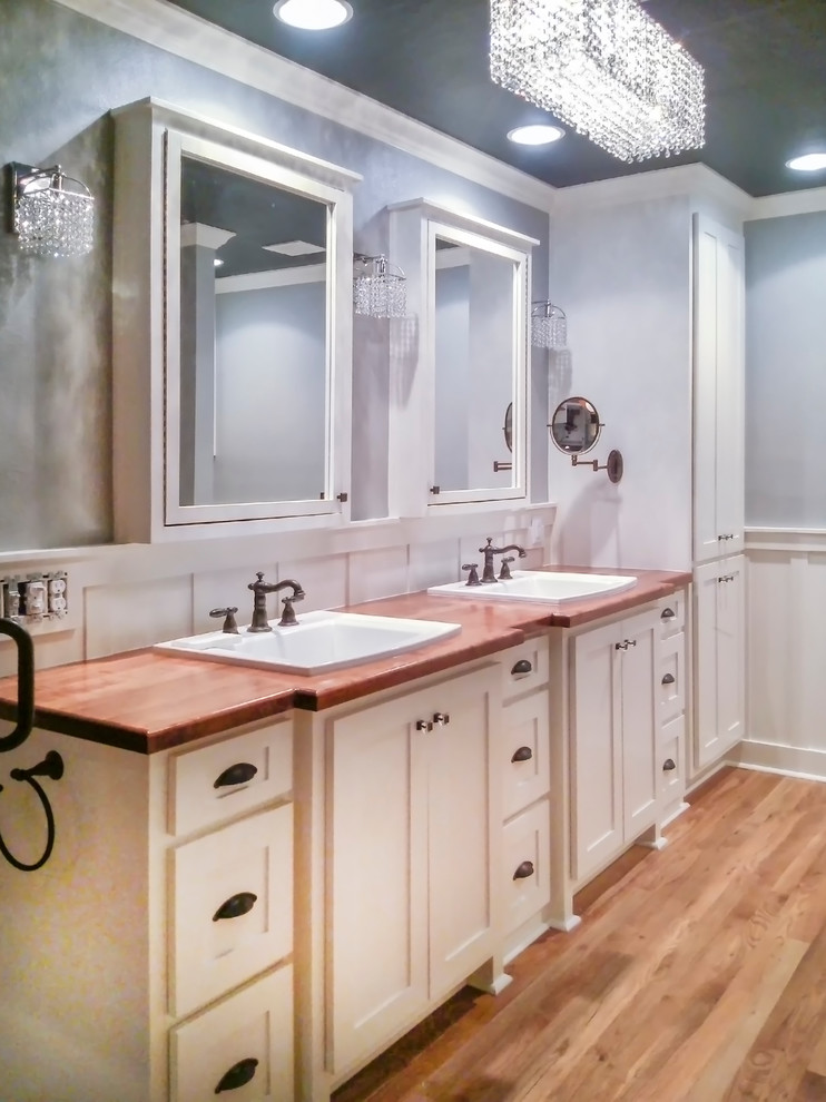This is an example of a mid-sized country master bathroom in Other with shaker cabinets, white cabinets, blue walls and wood benchtops.