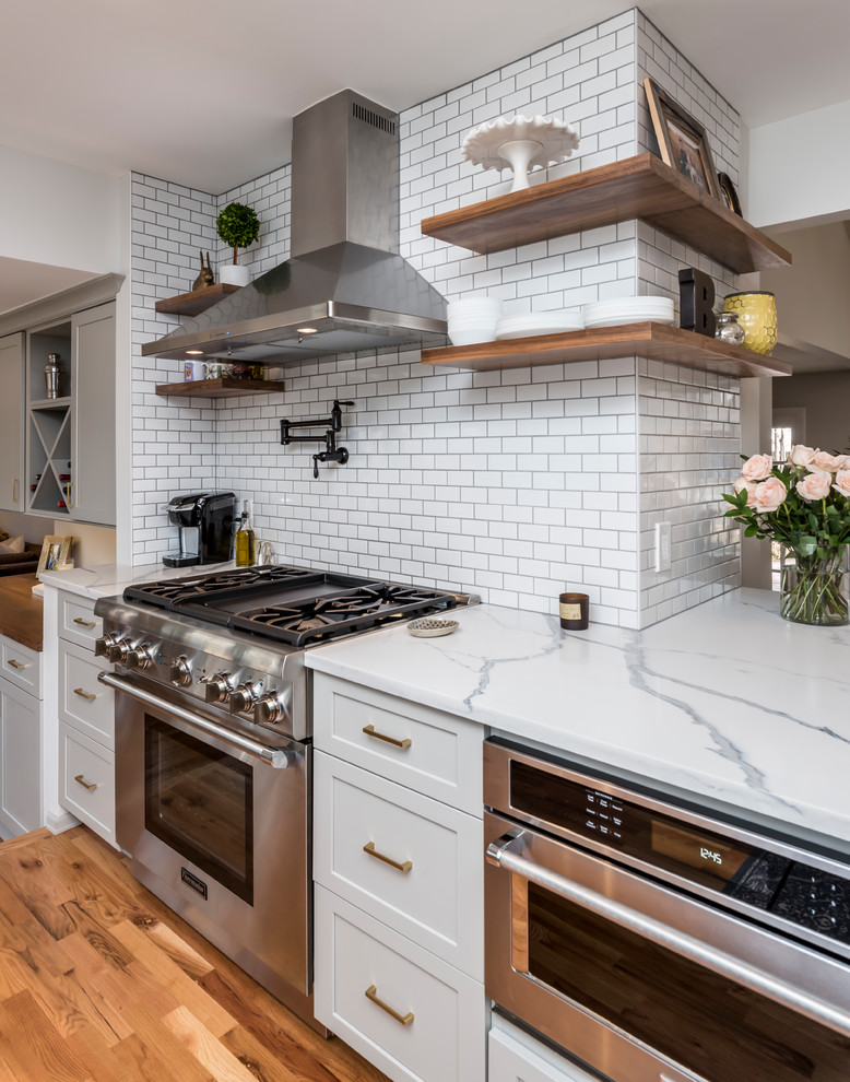 Mid-sized transitional galley medium tone wood floor eat-in kitchen photo in Denver with a farmhouse sink, shaker cabinets, gray cabinets, quartz countertops, white backsplash, porcelain backsplash, stainless steel appliances, a peninsula and white countertops