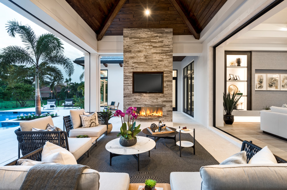 Photo of a beach style backyard patio in Other with tile, a roof extension and with fireplace.