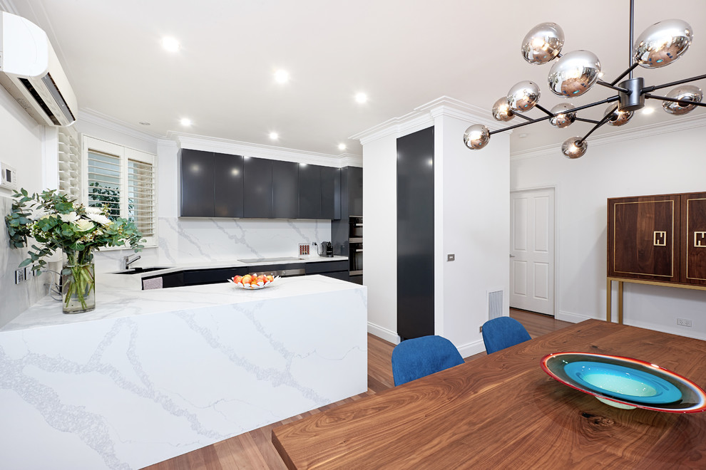 Design ideas for a mid-sized modern u-shaped kitchen pantry in Melbourne with an undermount sink, black cabinets, solid surface benchtops, white splashback, stone slab splashback, stainless steel appliances, light hardwood floors, brown floor and white benchtop.
