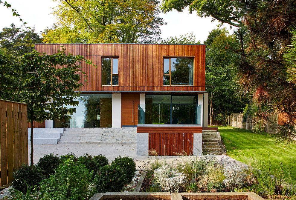 Photo of a small contemporary two-storey exterior in Manchester with wood siding and a flat roof.