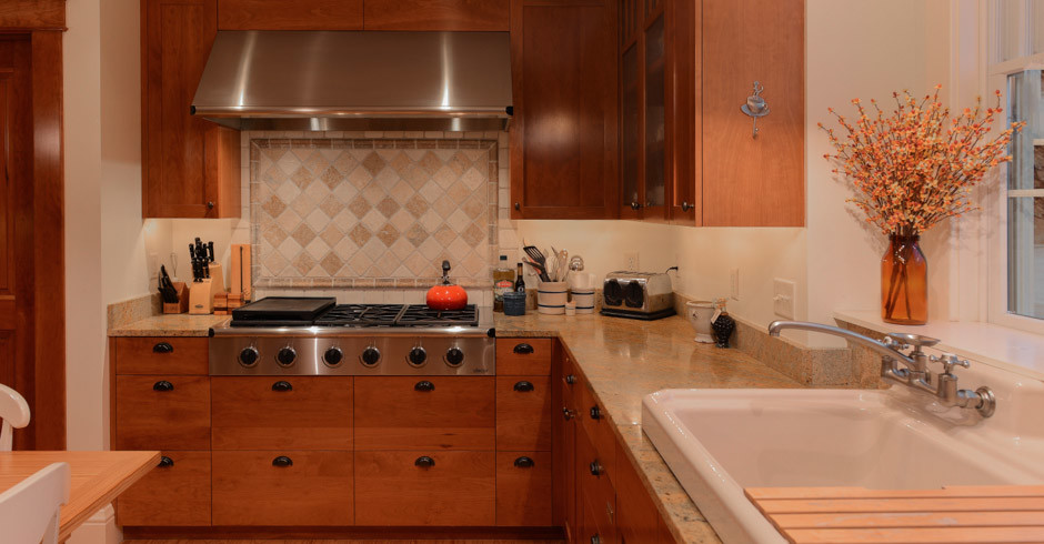 Example of a large arts and crafts u-shaped light wood floor and brown floor eat-in kitchen design with shaker cabinets, medium tone wood cabinets, granite countertops, stainless steel appliances, an island and a drop-in sink