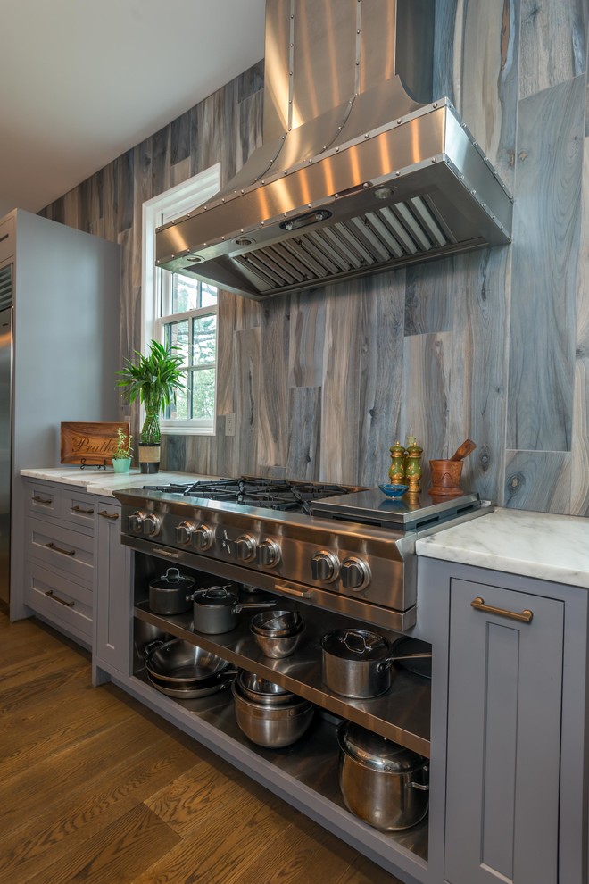 This is an example of a large transitional l-shaped kitchen in Other with an undermount sink, shaker cabinets, grey cabinets, marble benchtops, grey splashback, stainless steel appliances, medium hardwood floors, with island and grey benchtop.