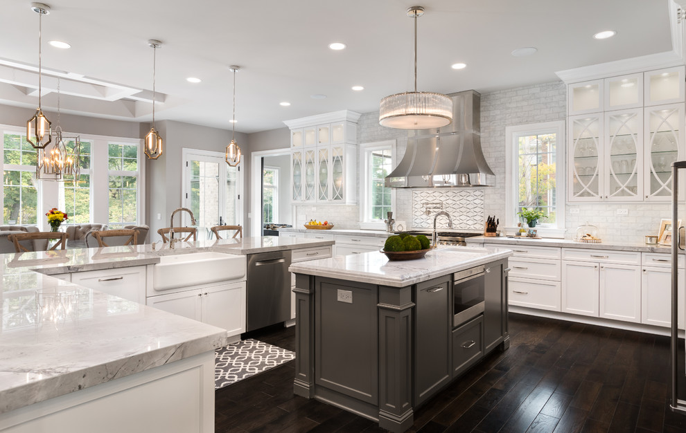 Large transitional l-shaped dark wood floor eat-in kitchen photo in Chicago with a farmhouse sink, glass-front cabinets, white cabinets, marble countertops, white backsplash, mosaic tile backsplash, stainless steel appliances and an island