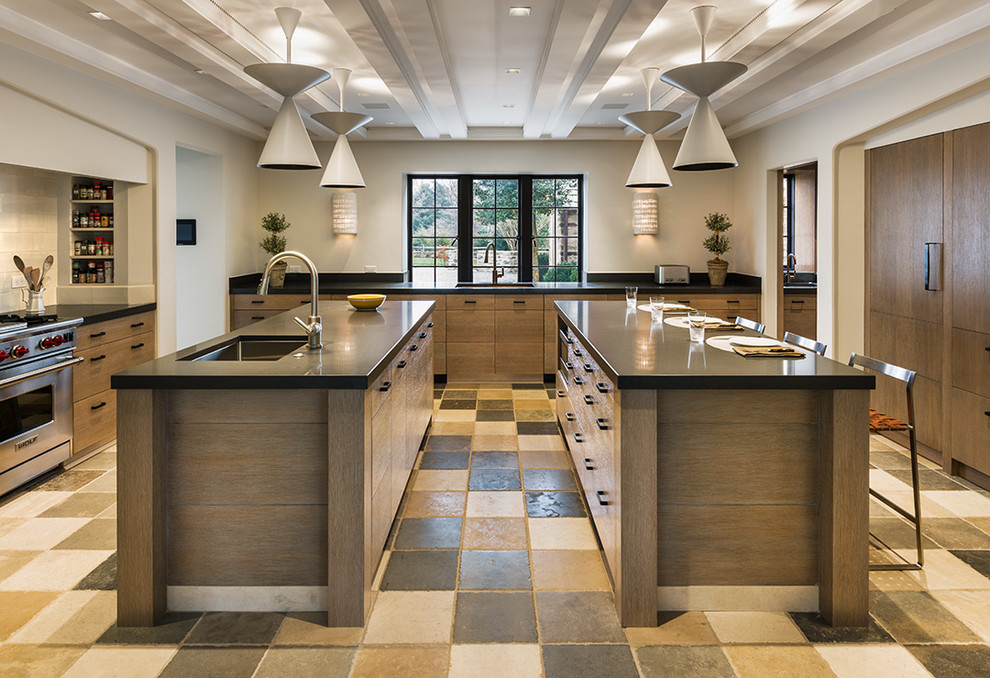Inspiration for a large transitional l-shaped eat-in kitchen in Philadelphia with an undermount sink, flat-panel cabinets, light wood cabinets, limestone benchtops, ceramic splashback, stainless steel appliances, travertine floors and multiple islands.