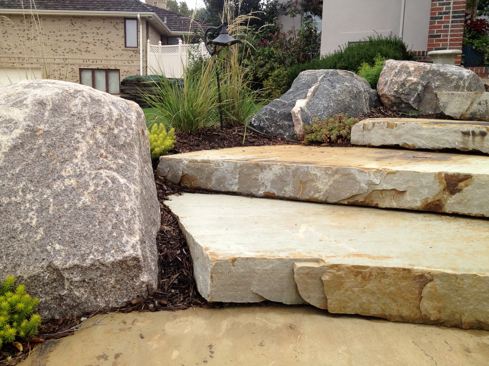 Photo of a large traditional front yard full sun garden in Omaha with a garden path and natural stone pavers.