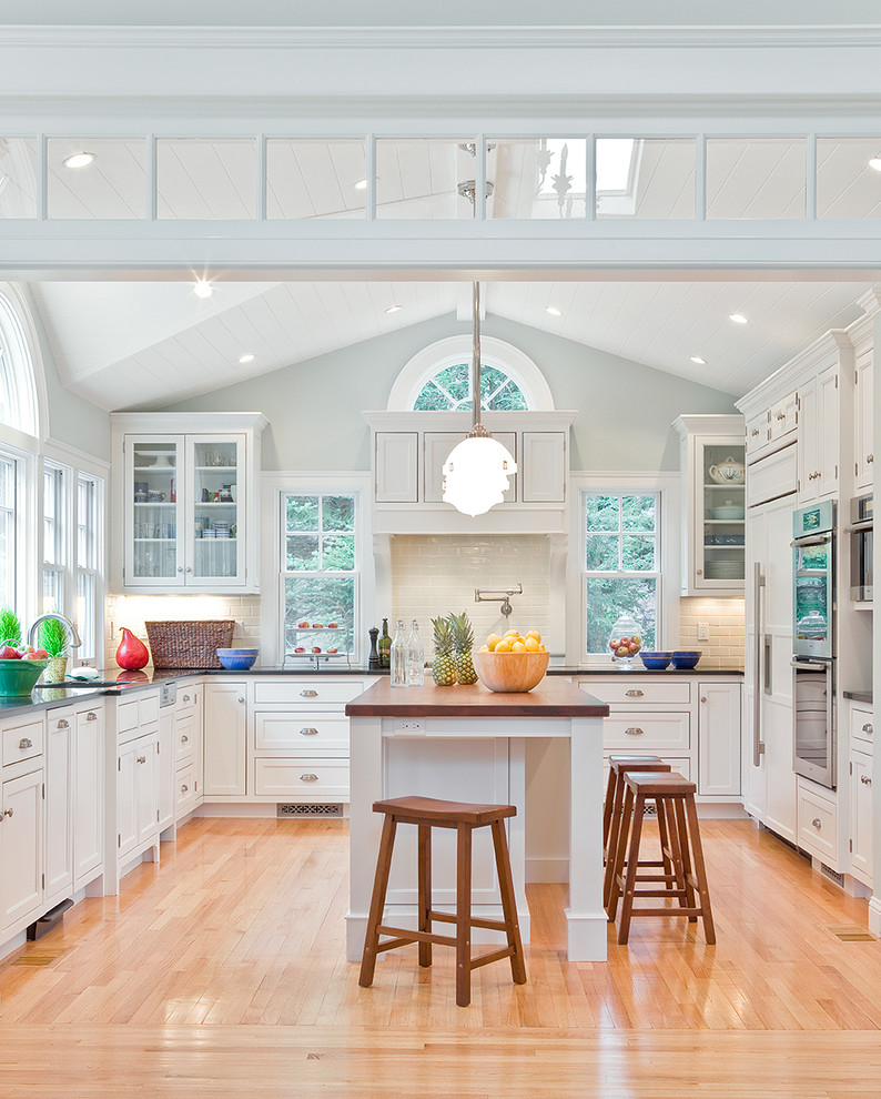 Inspiration for a traditional u-shaped kitchen in Boston with wood benchtops, beaded inset cabinets, white cabinets and panelled appliances.