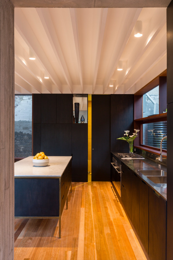 Design ideas for a mid-sized contemporary galley eat-in kitchen in Sydney with an integrated sink, flat-panel cabinets, black cabinets, marble benchtops, stainless steel appliances, medium hardwood floors and with island.