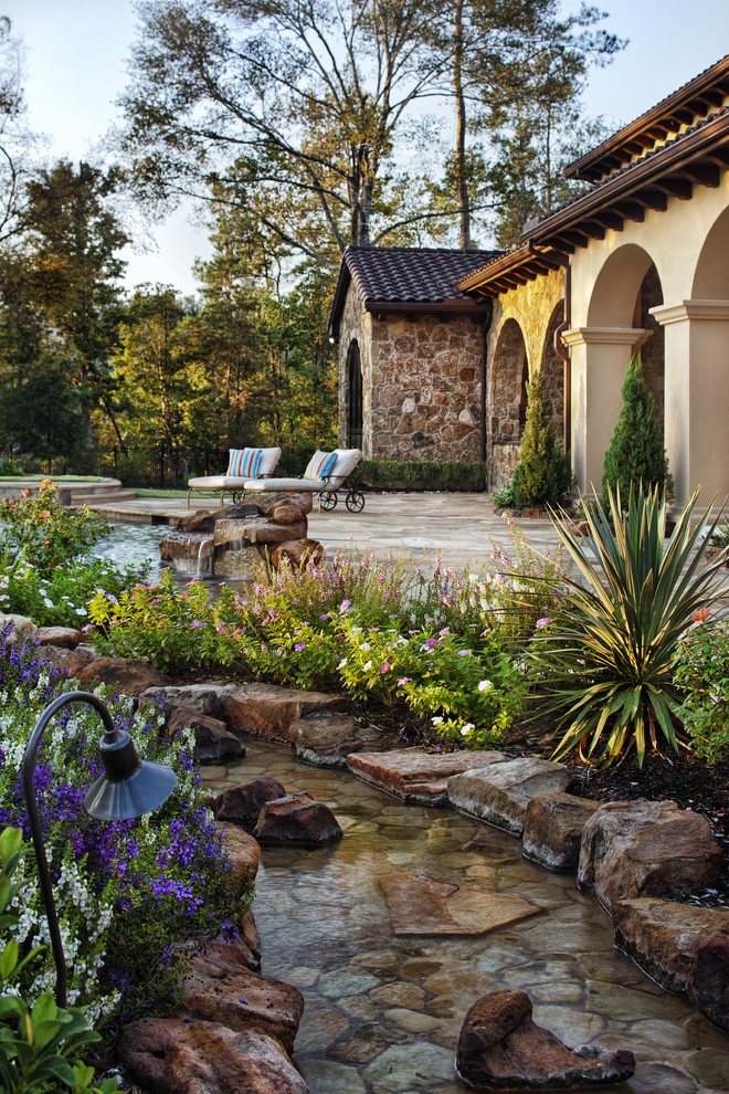 This is an example of a mediterranean garden in Austin with a water feature.