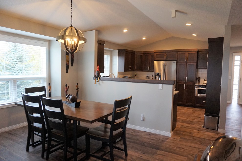 Mid-sized transitional u-shaped dark wood floor and brown floor kitchen photo in Calgary with a farmhouse sink, shaker cabinets, dark wood cabinets, granite countertops, white backsplash, subway tile backsplash, stainless steel appliances and a peninsula