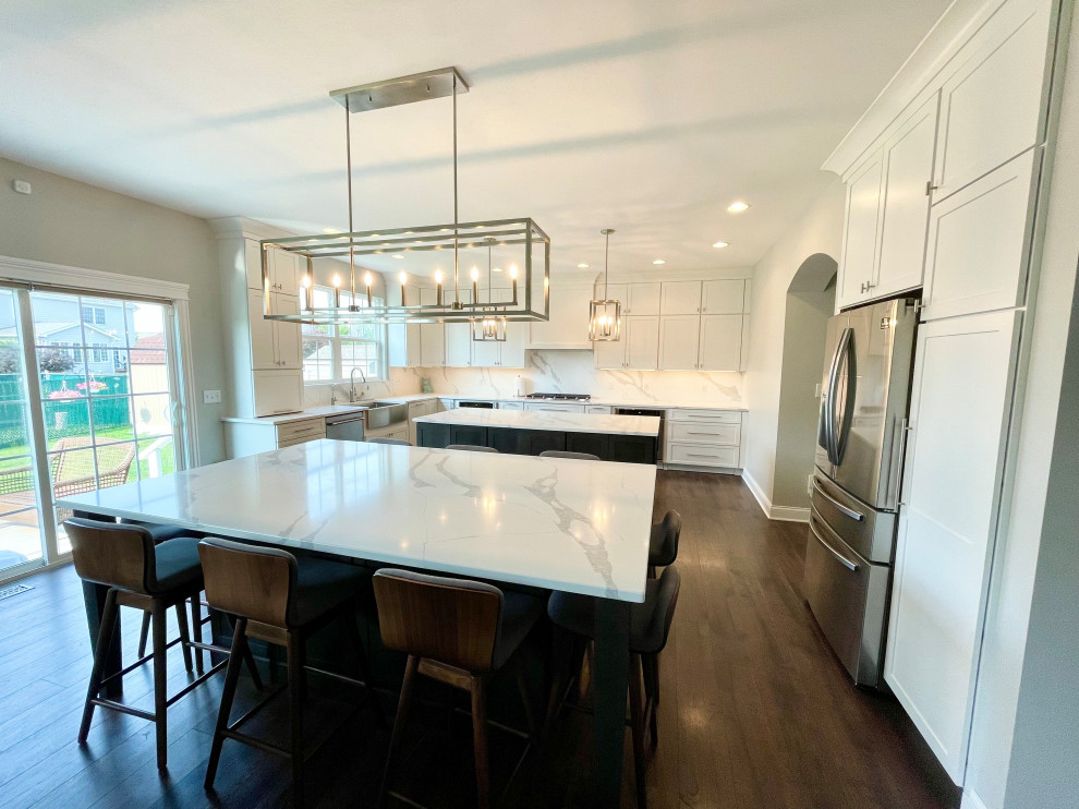 Large transitional u-shaped medium tone wood floor and brown floor eat-in kitchen photo in Chicago with a farmhouse sink, shaker cabinets, white cabinets, quartz countertops, white backsplash, quartz backsplash, stainless steel appliances, two islands and white countertops