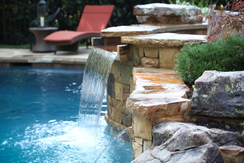 Design ideas for a mid-sized arts and crafts backyard custom-shaped lap pool in Other with a hot tub and natural stone pavers.