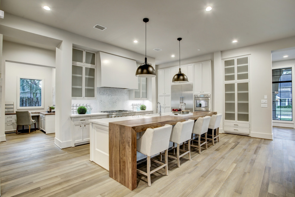 Expansive contemporary galley kitchen in Houston with a submerged sink, shaker cabinets, grey cabinets, engineered stone countertops, white splashback, stainless steel appliances, medium hardwood flooring, multiple islands, brown floors and grey worktops.