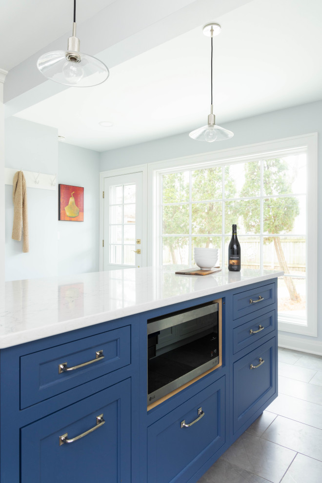 Idéer för att renovera ett mellanstort vintage vit vitt kök och matrum, med en undermonterad diskho, luckor med infälld panel, vita skåp, bänkskiva i kvarts, vitt stänkskydd, rostfria vitvaror, klinkergolv i keramik, en köksö och grått golv