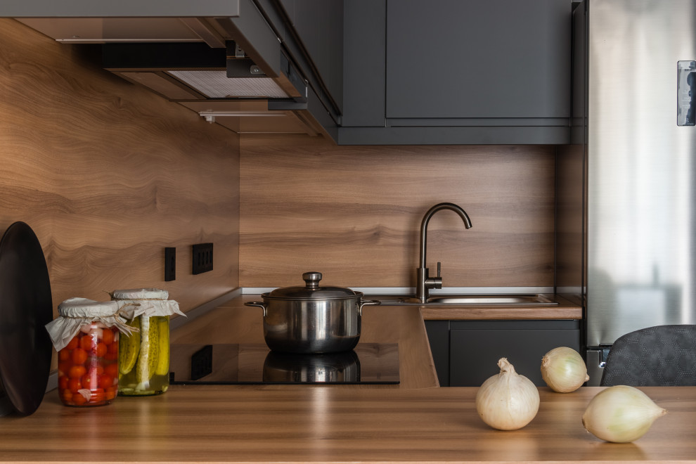 Foto di una cucina a L design di medie dimensioni con lavello sottopiano, ante lisce, ante nere, top in laminato, paraspruzzi beige, pavimento in vinile, pavimento beige e top beige