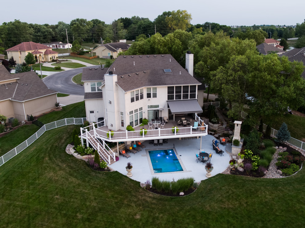 Imagen de piscina alargada clásica extra grande rectangular en patio trasero con paisajismo de piscina y losas de hormigón