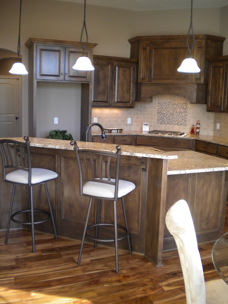 Mid-sized traditional l-shaped open plan kitchen in Omaha with granite benchtops, beige splashback, raised-panel cabinets, ceramic splashback, dark hardwood floors and with island.