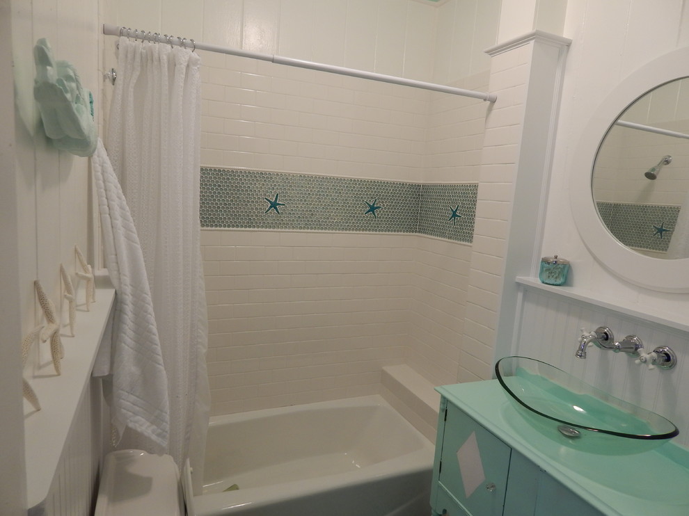 Small beach style bathroom in Tampa with turquoise cabinets, wood benchtops, white tile, ceramic tile, a drop-in tub, a two-piece toilet, a vessel sink, white walls and slate floors.