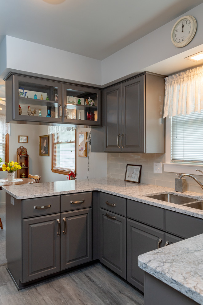 Eat-in kitchen - small transitional u-shaped vinyl floor and gray floor eat-in kitchen idea with a double-bowl sink, raised-panel cabinets, gray cabinets, quartz countertops, white backsplash, subway tile backsplash, white appliances, no island and multicolored countertops