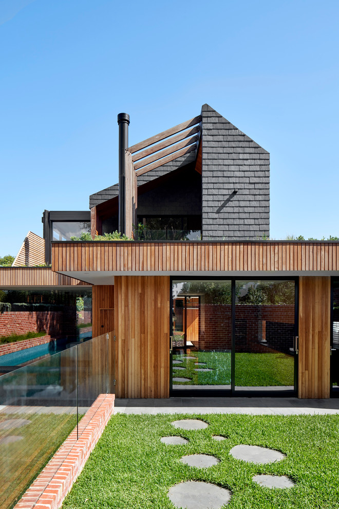 Contemporary black house exterior in Melbourne with wood siding, a gable roof and a shingle roof.