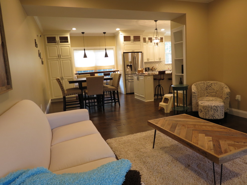 Example of a large transitional galley dark wood floor and brown floor kitchen design with a double-bowl sink, raised-panel cabinets, white cabinets, granite countertops, white backsplash, porcelain backsplash, stainless steel appliances and an island