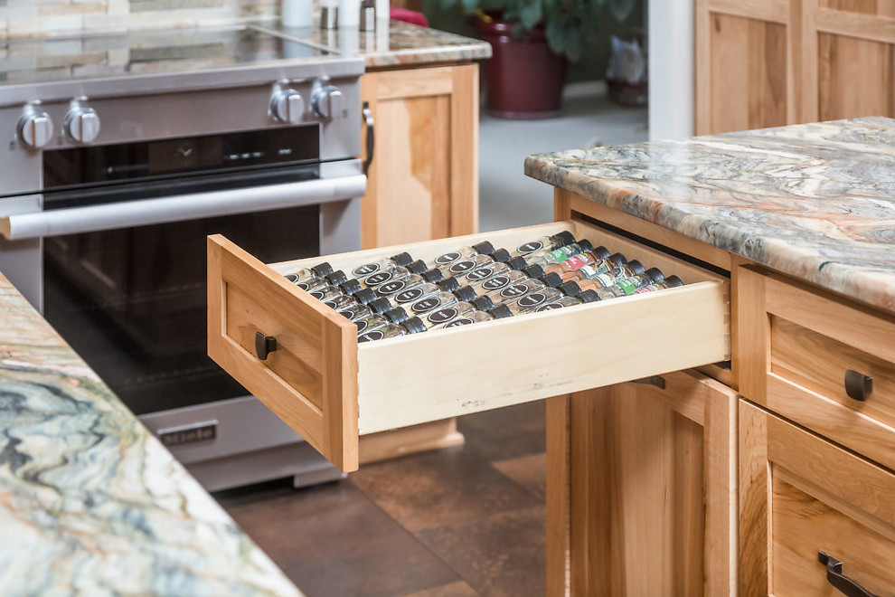 Example of a mid-sized mountain style vinyl floor kitchen design with an undermount sink, recessed-panel cabinets, light wood cabinets, granite countertops, stainless steel appliances and an island