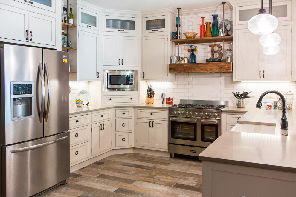 Mid-sized country u-shaped eat-in kitchen in St Louis with a farmhouse sink, beaded inset cabinets, white cabinets, quartzite benchtops, white splashback, subway tile splashback, stainless steel appliances, ceramic floors and a peninsula.