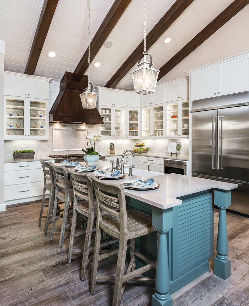 Design ideas for a transitional l-shaped kitchen in Miami with a farmhouse sink, glass-front cabinets, white cabinets, quartz benchtops, stainless steel appliances, with island, beige splashback and medium hardwood floors.