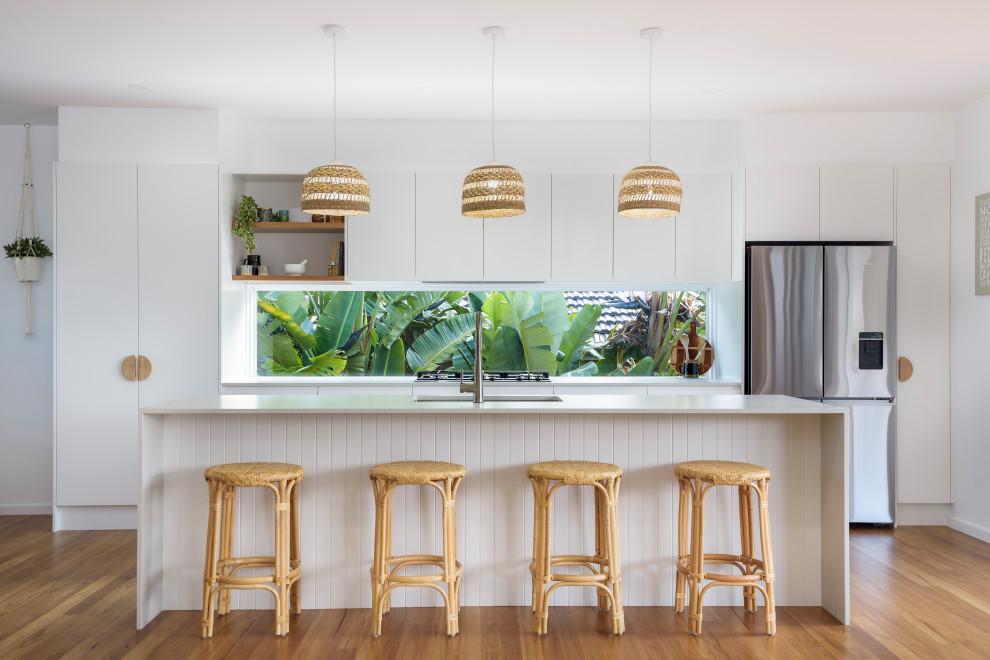This is an example of a small nautical galley kitchen/diner in Newcastle - Maitland with a submerged sink, flat-panel cabinets, white cabinets, engineered stone countertops, white splashback, window splashback, stainless steel appliances, an island and white worktops.