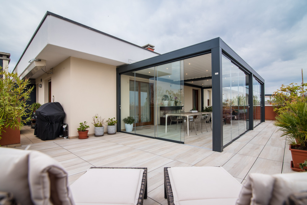 Immagine di una privacy sulla terrazza design di medie dimensioni, sul tetto e sul tetto con una pergola e parapetto in vetro