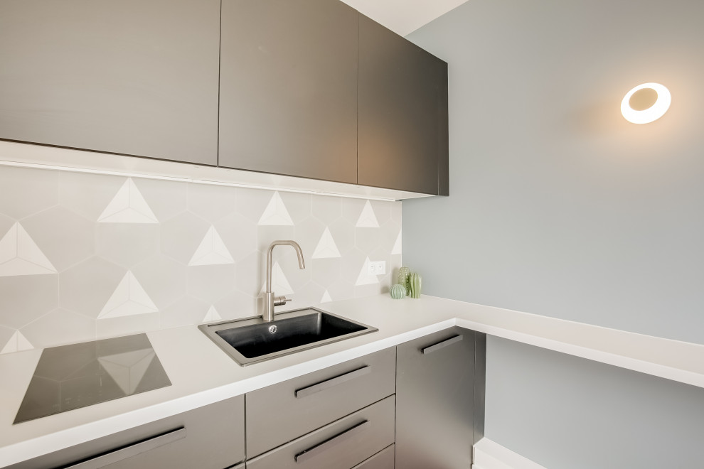 This is an example of a small contemporary single-wall open plan kitchen in Paris with an undermount sink, black cabinets, laminate benchtops, grey splashback, cement tile splashback, terra-cotta floors, no island, brown floor and white benchtop.