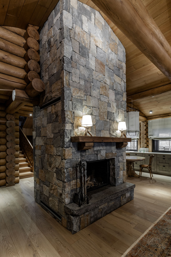 Imagen de sala de estar abierta industrial grande con chimenea lineal y marco de chimenea de piedra