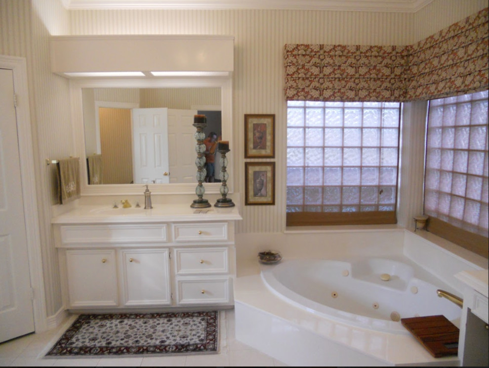 Mid-sized traditional master bathroom in Houston with recessed-panel cabinets, white cabinets, a corner tub, beige walls, porcelain floors, an integrated sink, solid surface benchtops, white floor and white benchtops.