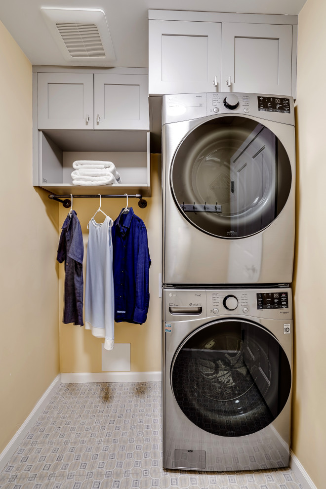 Foto di una piccola sala lavanderia tradizionale con ante in stile shaker, ante grigie, pareti gialle, pavimento in gres porcellanato, lavatrice e asciugatrice a colonna e pavimento blu