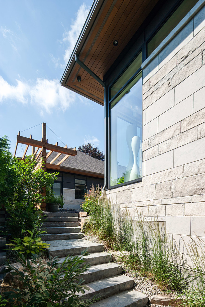 Photo of a contemporary sloped garden in Ottawa with natural stone pavers.