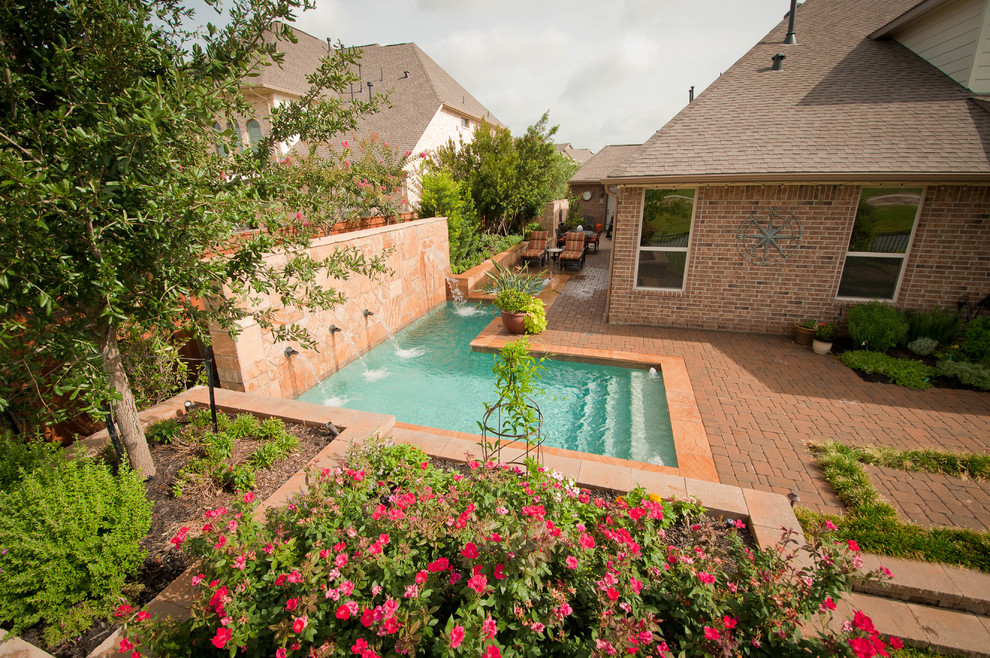 Photo of a mid-sized traditional side yard l-shaped pool in Houston with a hot tub and natural stone pavers.