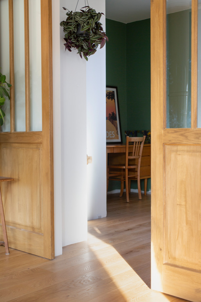 Mittelgroßes Retro Arbeitszimmer mit Arbeitsplatz, grüner Wandfarbe, hellem Holzboden und freistehendem Schreibtisch in Sonstige