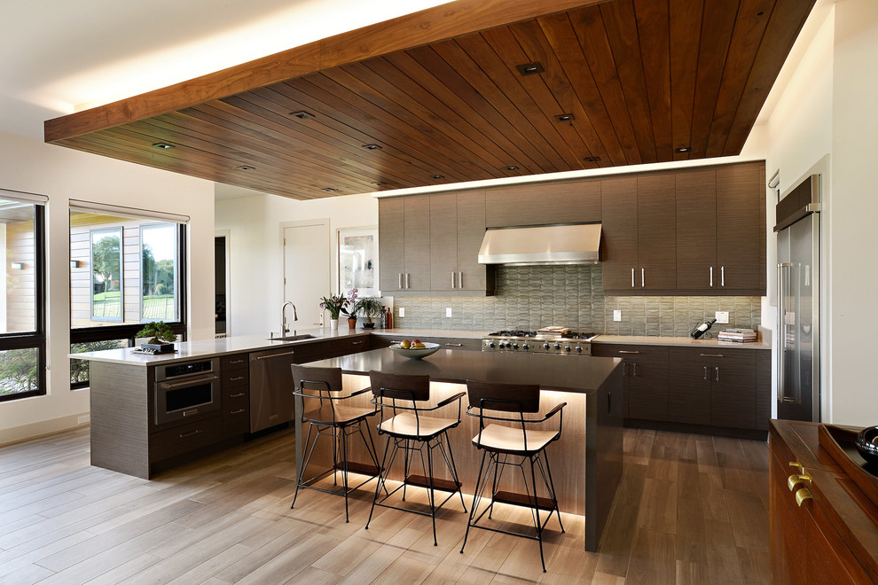 Inspiration for a mid-sized contemporary u-shaped eat-in kitchen in Dallas with an undermount sink, flat-panel cabinets, brown cabinets, quartz benchtops, green splashback, ceramic splashback, stainless steel appliances, medium hardwood floors, with island, brown floor and grey benchtop.