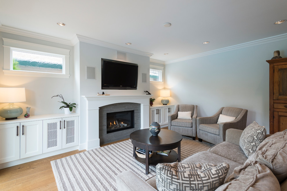 This is an example of a mid-sized contemporary enclosed family room in Vancouver with light hardwood floors, a standard fireplace, a stone fireplace surround, a built-in media wall and grey walls.