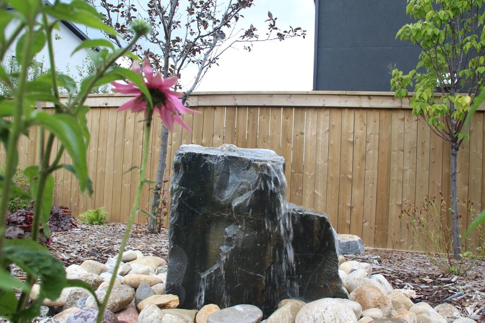 This is an example of a mid-sized transitional full sun front yard stone retaining wall landscape in Calgary.
