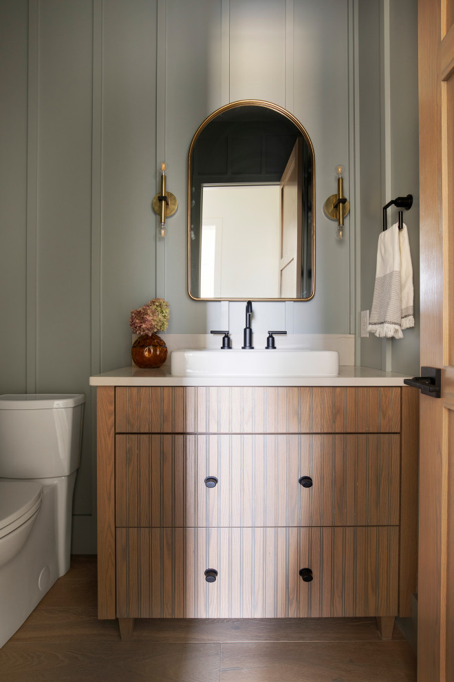This is an example of a large transitional powder room in Minneapolis with light wood cabinets, grey walls, light hardwood floors, engineered quartz benchtops, beige floor, white benchtops, a freestanding vanity and panelled walls.