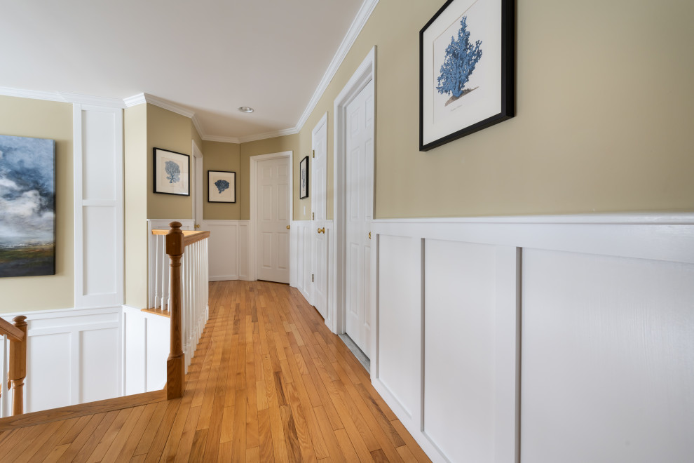 Mittelgroßes Foyer mit weißer Wandfarbe, hellem Holzboden, gewölbter Decke und Wandpaneelen in Sonstige