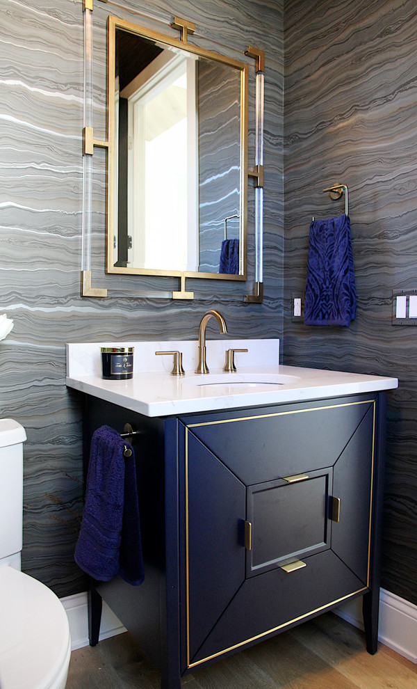This is an example of a transitional powder room in Other with furniture-like cabinets, blue cabinets, multi-coloured walls, light hardwood floors, an undermount sink and beige floor.