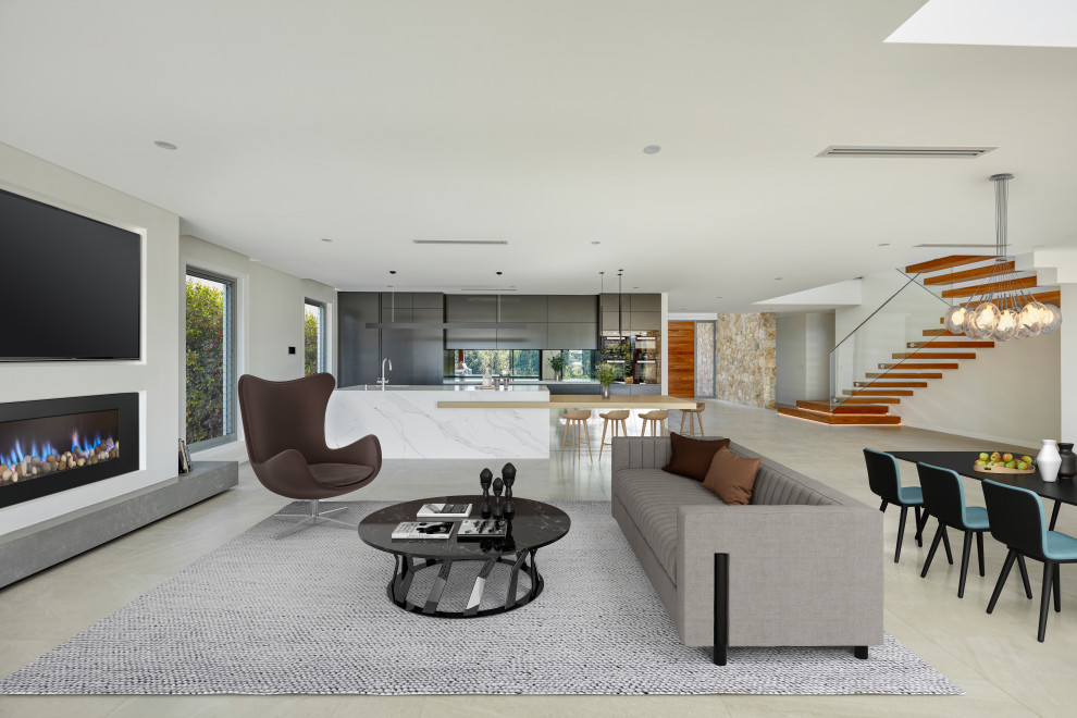 This is an example of an expansive contemporary open concept living room in Sydney with white walls, porcelain floors, a standard fireplace, a metal fireplace surround, a wall-mounted tv and grey floor.