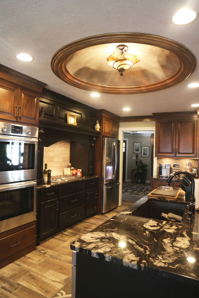 Example of a mid-sized transitional l-shaped porcelain tile eat-in kitchen design with an undermount sink, raised-panel cabinets, medium tone wood cabinets, granite countertops, beige backsplash, porcelain backsplash, stainless steel appliances and an island