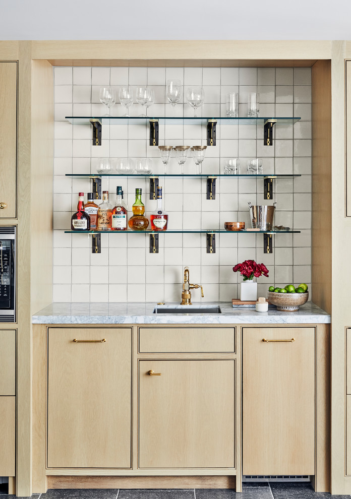 This is an example of a transitional single-wall wet bar in Los Angeles with an undermount sink, beaded inset cabinets, light wood cabinets, white splashback and white benchtop.
