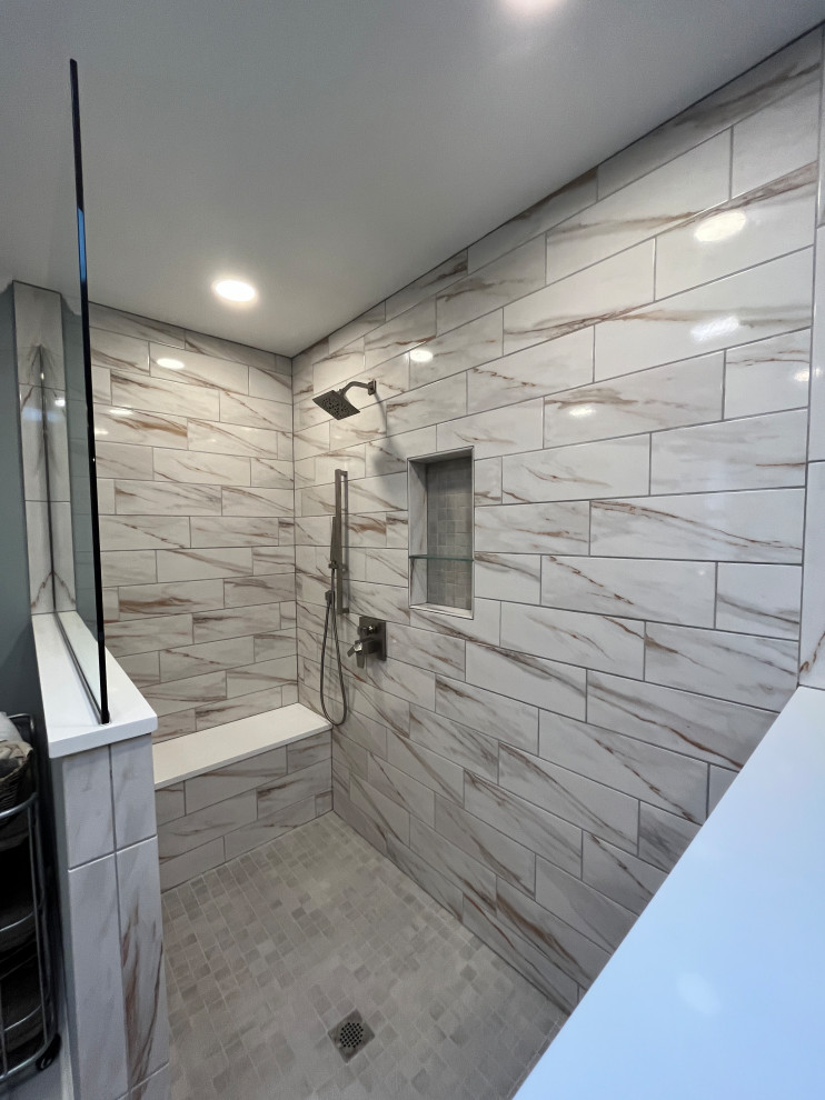 Photo of a large classic ensuite bathroom in Indianapolis with beaded cabinets, grey cabinets, a built-in shower, a one-piece toilet, multi-coloured tiles, porcelain tiles, grey walls, porcelain flooring, a submerged sink, granite worktops, white floors, an open shower, black worktops, a shower bench, double sinks and a built in vanity unit.