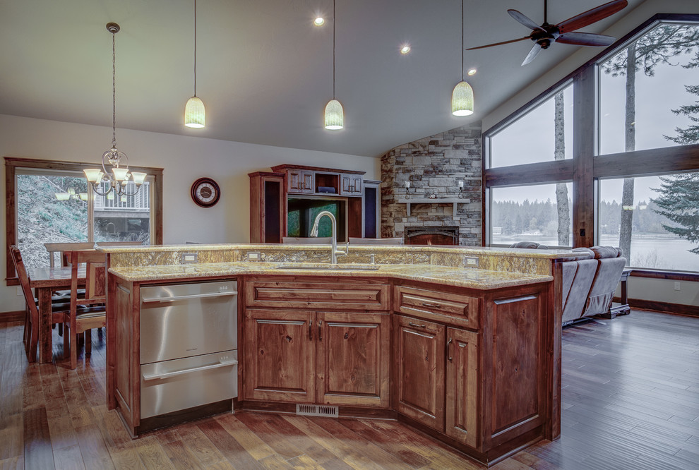 Example of a large mountain style u-shaped medium tone wood floor eat-in kitchen design in Seattle with an undermount sink, raised-panel cabinets, medium tone wood cabinets, granite countertops, beige backsplash, ceramic backsplash, stainless steel appliances and an island