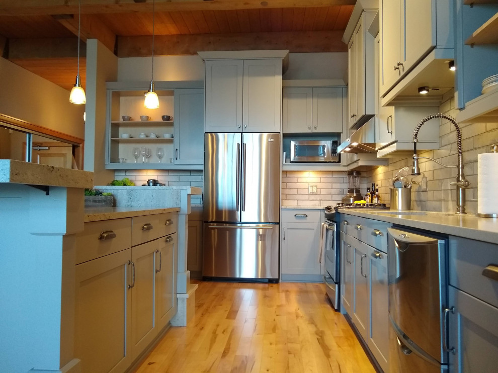 Mid-sized modern l-shaped eat-in kitchen in Milwaukee with a single-bowl sink, recessed-panel cabinets, grey cabinets, marble benchtops, grey splashback, ceramic splashback, stainless steel appliances, light hardwood floors, with island, beige floor, grey benchtop and wood.