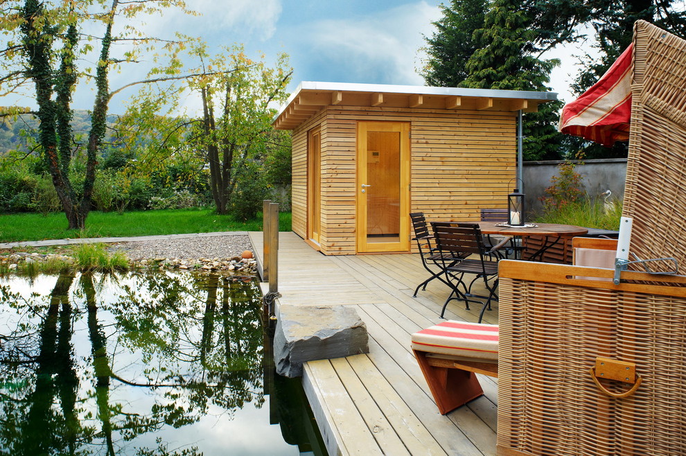 Inspiration for a large country backyard custom-shaped natural pool in Cologne with decking and a pool house.